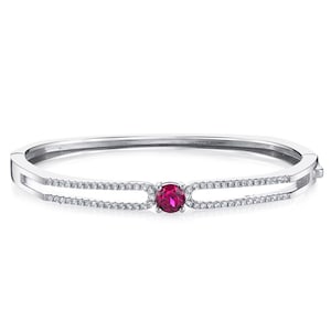 May include: A silver-toned hinged bangle bracelet featuring a central round-cut vibrant red gemstone. The band is split into two parallel rows, each encrusted with small clear white stones that extend from the center setting to the sides.