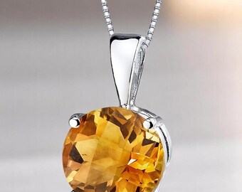 Puede incluir: Un collar con colgante de plata con una gran gema de citrino redonda y facetada. El citrino es de un color amarillo dorado cálido, engastado en un engaste de plata pulida y sencilla. La cadena es de diseño delicado.