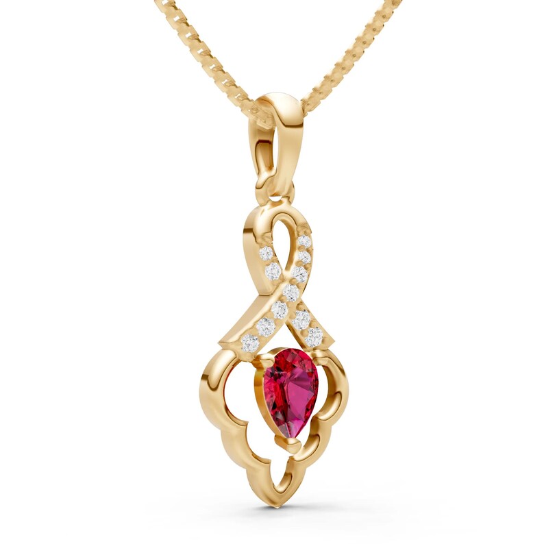 May include: A gold-colored pendant necklace featuring a teardrop-shaped, red gemstone. The pendant has a ribbon-like design with small, clear gemstones. The necklace chain is also gold-colored.
