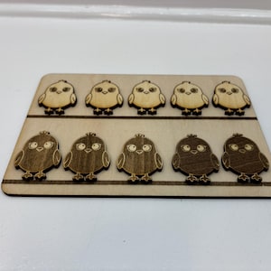 May include: A wooden plaque with ten laser-cut chick designs. The chicks are arranged in two rows of five, each with detailed eyes, beaks, and feet. The plaque is made of light-coloured wood with a natural finish.