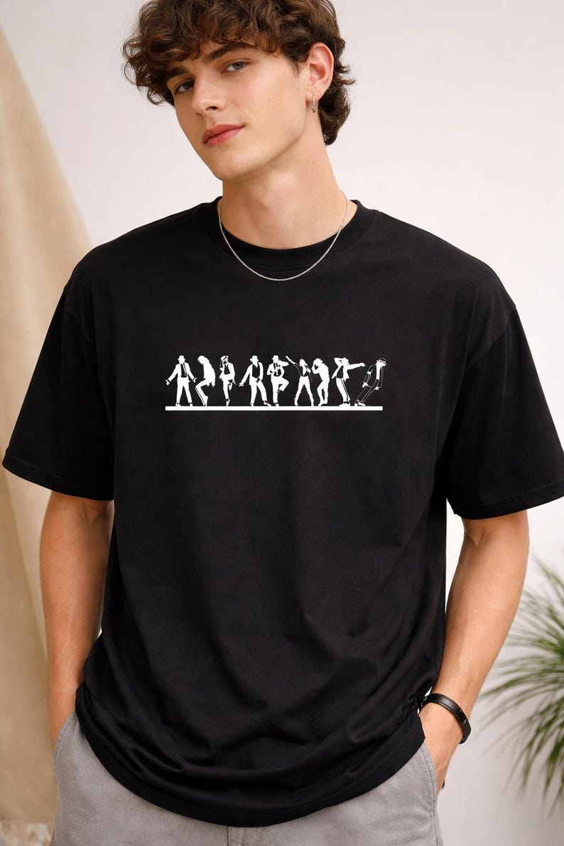 May include: Black t-shirt featuring a white graphic of stylized figures in various poses. The design is centered on the chest. The shirt has short sleeves and a crew neck. The model is wearing a silver chain.