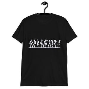 May include: Black t-shirt featuring a white silhouette of a line of dancers in various poses. The design includes figures in hats and suits, with one figure leaning forward. The shirt is hanging on a black hanger.