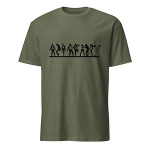 May include: Olive green t-shirt featuring a black graphic of stylized figures in various dance poses. The figures are arranged in a horizontal line across the chest of the shirt. The t-shirt has short sleeves and a crew neck.