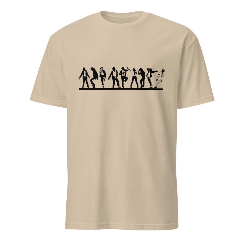May include: A tan t-shirt featuring a black silhouette of a line of people in various dance poses. The figures are depicted in a stylized, minimalist design, creating a dynamic and rhythmic visual effect. The shirt is made of a soft, comfortable material.