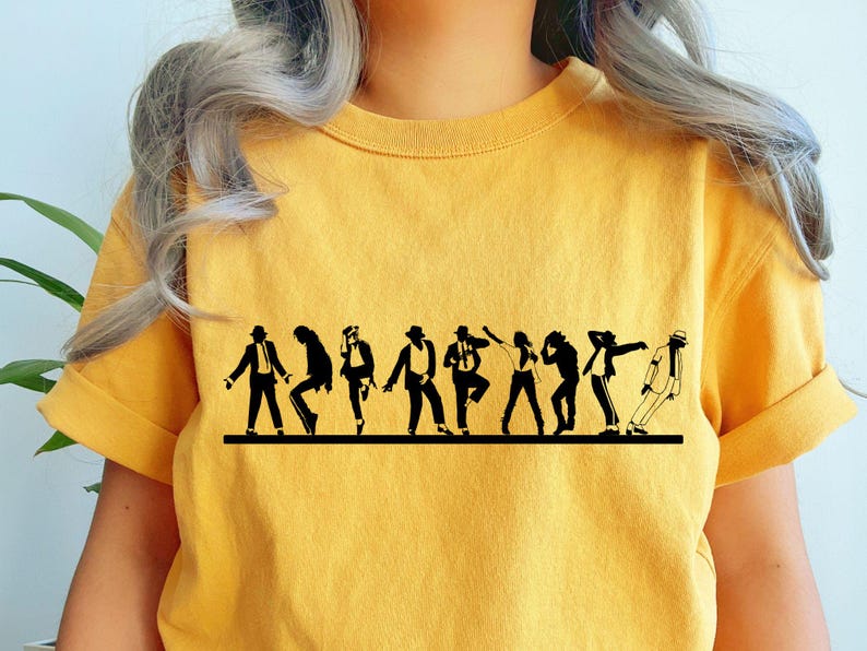 May include: Mustard yellow t-shirt featuring a black silhouette of a group of people in various dance poses. The graphic is a line of figures, each in a different dance move, on a horizontal black line.