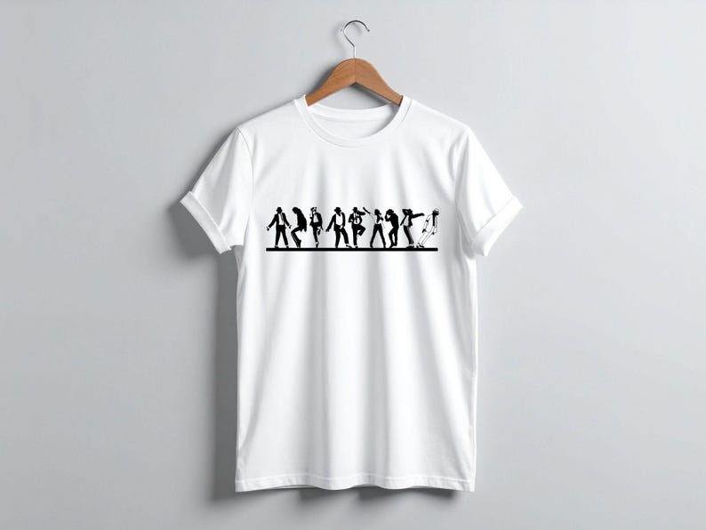 May include: White t-shirt with a black graphic of stylized figures in various dance poses. The design spans the chest area of the shirt. The shirt is hanging on a wooden hanger against a plain gray background.