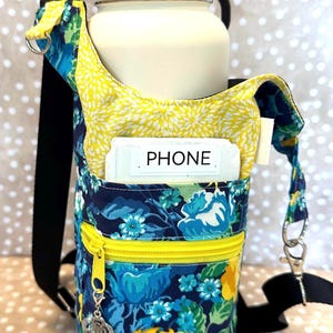May include: A black and yellow floral water bottle carrier with a zippered pocket and a black strap. The carrier has a label that says "PHONE".