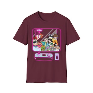 May include: Burgundy t-shirt with a graphic of a claw machine filled with cartoon characters. The claw machine has a pink border and the text "抓取" in pink.