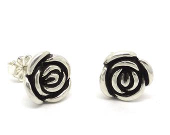 Op de afbeelding: Een paar zilveren oorbel studs met een roos ontwerp. De rozen zijn gedetailleerd en hebben een zwarte afwerking.
