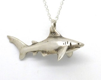 Op de afbeelding: Een zilveren haai hanger ketting. De haai is gedetailleerd en realistisch, met een zilveren ketting.