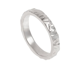 May include: A silver ring with a textured, hammered finish. The ring is simple and modern in style.