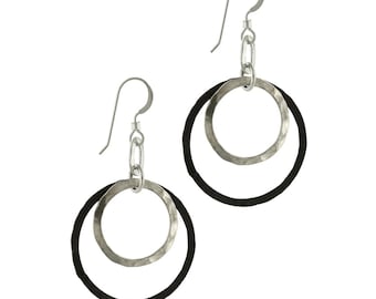 May include: A pair of silver hoop earrings with a black leather circle around each hoop.