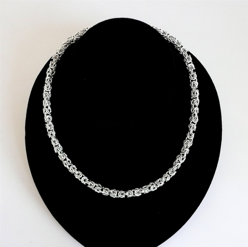 May include: A silver chain necklace with a byzantine weave pattern.