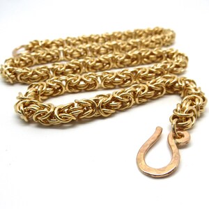 May include: A gold chain necklace with a unique woven design and a simple hook clasp.