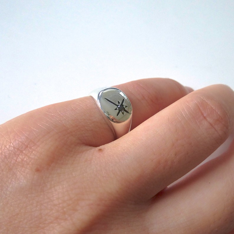 May include: A silver signet ring featuring a black star design.