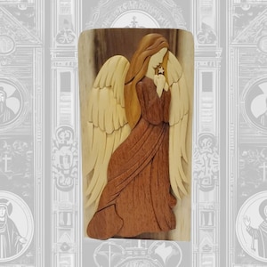 May include: Wooden angel sculpture with a light brown and dark brown color scheme. The angel has long hair, large wings, and is holding a star. The sculpture is made of layered wood and has a detailed design.