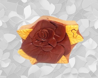 May include: A wooden box carved in the shape of a rose. The rose is a deep reddish-brown color, with yellow leaves. The box is made of wood and has a natural finish. The box is a decorative item.