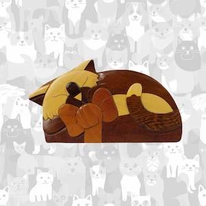 May include: A wooden cat-shaped puzzle box with a brown, yellow, and orange finish. The cat is lying on its side with its tail curled around its body. The box is intricately carved and has a hidden compartment.
