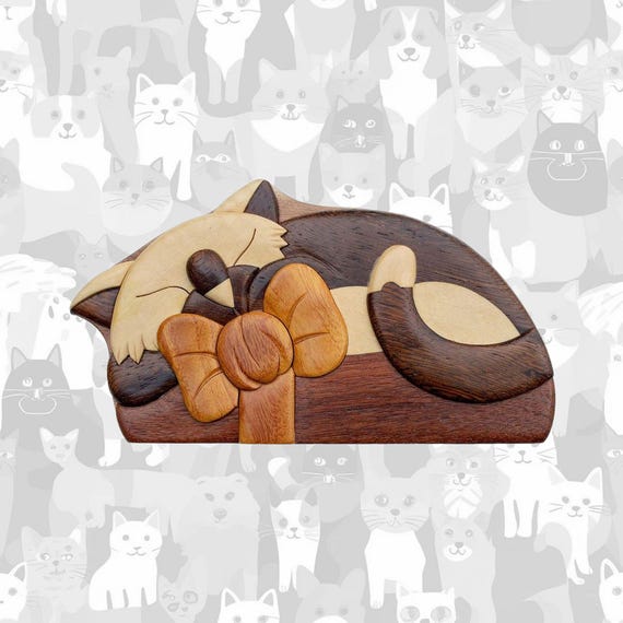 A hand-carved wooden puzzle box with a hidden secret compartment — you have to solve it to open it, and there's a charming cat-with-bow design on top.