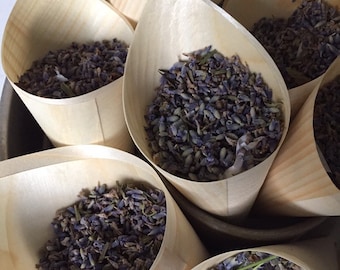 May include: Wooden cones filled with dried lavender flowers. The cones are arranged in a metal bowl.