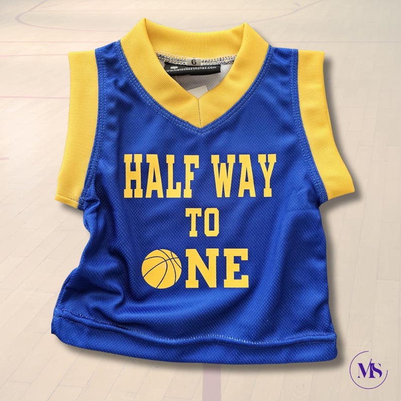 Puede incluir: Una camiseta de baloncesto azul y amarilla con el texto "HALF WAY TO ONE" y un gr&aacute;fico de baloncesto.