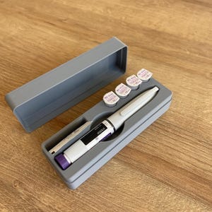 May include: A gray plastic case with a white pen and four small white vials with purple lids. The vials are labeled "BD Viva 30G x 8mm" and "CE". The pen is labeled "BD Viva 1.1-1.5 IU/mL".