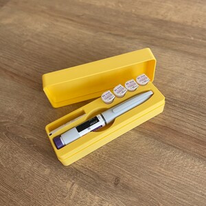 May include: A yellow plastic case with a white pen-like device and five small white vials with purple labels. The vials have the text "BD Viva 30G x 8mm" and "CE" printed on them.