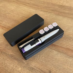 May include: A black case with a white pen and four small round containers with purple labels that say "BD Viva 30G x 1/2", "BD Viva 30G x 1/2", "BD Viva 30G x 1/2", and "BD Viva 30G x 1/2".