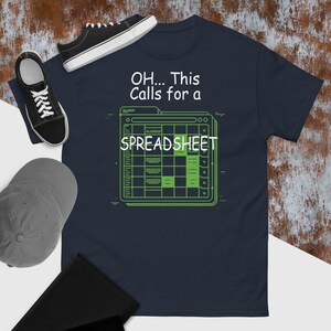 Puede incluir: Camiseta azul marino con un gráfico de hoja de cálculo verde y el texto "OH... This Calls for a SPREADSHEET". La camiseta se combina con zapatillas negras y una gorra de béisbol gris.