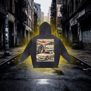 May include: A black hooded sweatshirt featuring a graphic print on the back. The design displays three panels showing a tan sports car from different angles, including the rear, a wheel, and the front, with the text S15 printed at the bottom.