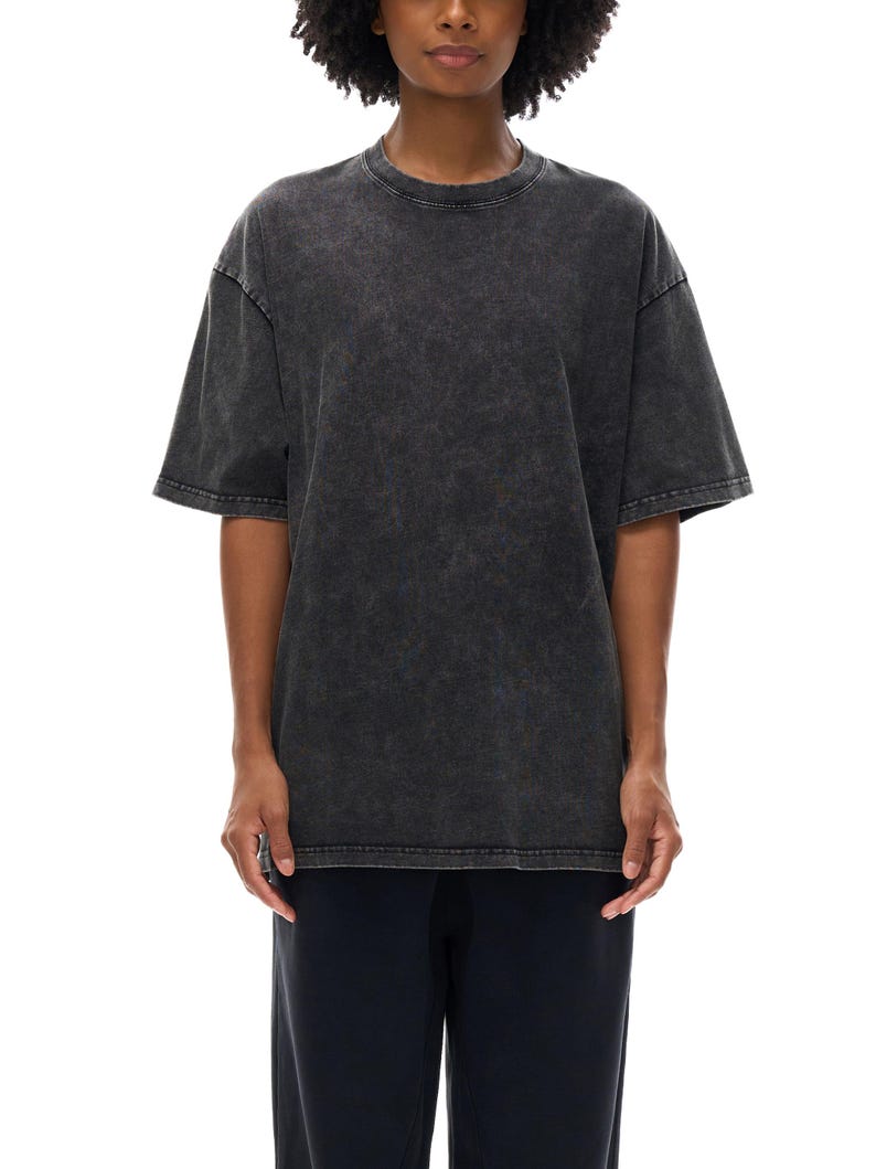 K&ouml;nnte beinhalten: Ein &uuml;bergro&szlig;es T-Shirt in Anthrazit mit Rundhalsausschnitt und kurzen &Auml;rmeln. Das Shirt hat ein verwaschenes, strukturiertes Aussehen. Das Model tr&auml;gt auch eine dunkelblaue Hose.
