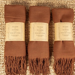 May include: Three brown pashmina scarves with fringe, each with a white label that reads "To Have and To Hold, You Get Cold".