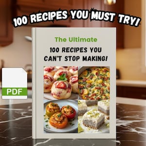 May include: A cookbook titled "The Ultimate 100 Recipes You Can't Stop Making!" with images of various dishes. The cover features the text "100 RECIPES YOU MUST TRY!" and a PDF icon. The book is on a black marble surface.