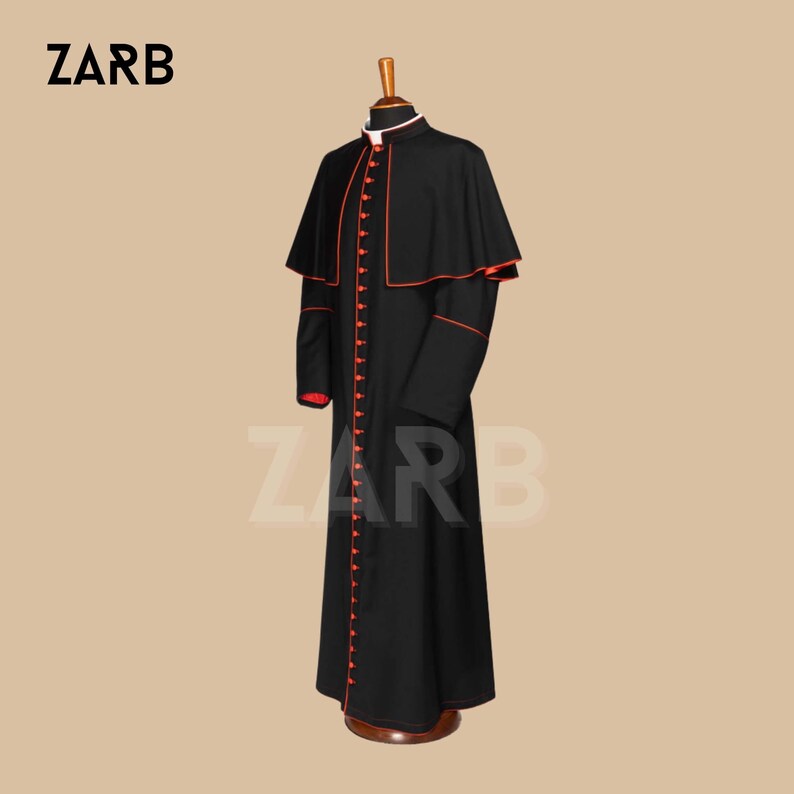 May include: A black cassock with a red trim and a red button closure. The cassock has a cape-like collar and is worn by a clergy member.