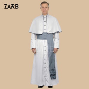May include: A white clerical robe with a matching cape and a gray sash. The robe has a button-down front and gray trim. The cape is trimmed in gray and the sash has a tassel. The word "ZARB" is in the upper left corner.