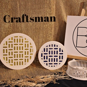 May include: Two white plastic drain covers with different colored grid patterns. The larger cover has a yellow grid pattern and the smaller cover has a blue grid pattern. The covers are on a gold background. The text "Clever Covers" is on a white sign behind the covers.