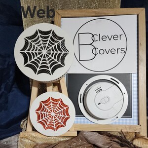 May include: White round covers with spiderweb designs in black and red. A white smoke detector is also visible. The image includes a sign with the text "Clever Covers" and the word "Web".
