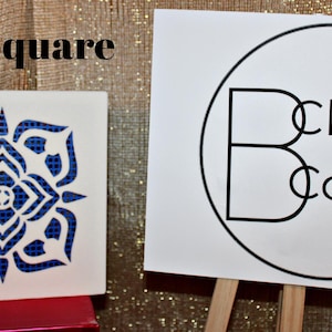 May include: A white square tile with a blue floral design and the text "Axel Square". Next to it is a sign with the text "Clever Covers" inside a black circle.