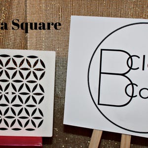 May include: White square stencil with a geometric pattern of overlapping circles and flower shapes. The stencil is labeled "Maya Square". The background is a gold fabric. A white sign with a black circle and the text "Clever Covers" is in the background.