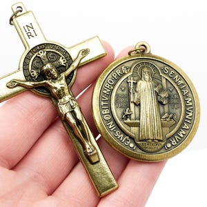 Puede incluir: Un crucifijo de metal dorado con una figura de Jesucristo y una medalla redonda con una representación de San Antonio de Padua. La medalla tiene la inscripción "S. Antonius.  IN. RI.  OBITV. NRO. PRA.  SEN.TIA.  MVN.IA.  VIV.I.  CVS.  IN.  S31.  DES.  V.  ECCL.  MYSTICIS".