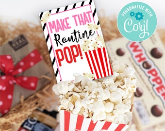 May include: A red and white striped popcorn box with a white card that says "Make That Routine POP!" on it. The card has a pink and black striped background. The image is a close-up of the popcorn box and card.