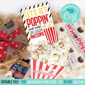 May include: A popcorn box filled with popped popcorn, with a tag that reads "LET'S GET POPPIN' and make THIS SEASON AWESOME". The box has red and white stripes. A box of Whoppers is in the background.