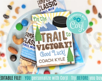 Puede incluir: Una etiqueta de regalo imprimible con un diseño de montaña y pino. El texto dice "On the TRAIL to VICTORY! Good Luck! COACH KYLE". La etiqueta está personalizada con el nombre "Corjl".