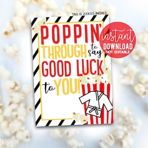 Op de afbeelding: Een printbare tag van 2,5 x 3,5 inch met een rood-wit-zwarte gestreepte achtergrond. De tag heeft een wit karatepak met een zwarte band en de tekst "Poppin' through to say good luck to you!" in rood, wit en geel. De tag is omringd door popcorn.