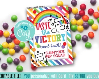 Op de afbeelding: Een kleurrijk afdrukbaar label met een regenboog, muzieknoten en de tekst "Taste the Victory! Good Luck! Sunnyside Pep Squad". Het label is 2,5 inch bij 3,5 inch.