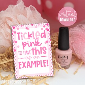 Op de afbeelding: Roze en witte printbare cadeau-tag met de tekst "Tickled pink to have this as an example!" met roze confetti en strepen. De tag ligt naast een flesje roze nagellak.