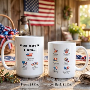 May include: Two white ceramic mugs with patriotic designs. The front mug says "GOD SAYS I am..." with "Empowered," "Loved," and "Precious" graphics. The back mug says "Unique," "Treasured," "Protected," "Brave," "Strong," and "Important."