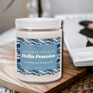 May include: A white jar candle with a white lid, featuring a blue label with the text "Goodbye Tension Hello Pension" and "the calming scent of being retired." The candle sits on a wooden board.