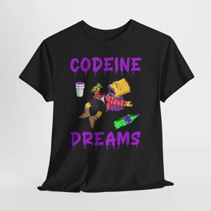 May include: A black short-sleeve t-shirt featuring a graphic of a cartoon character in a red jacket, black shorts, and tan shoes. The text CODEINE DREAMS is printed in purple with a dripping effect. A white cup and a green bottle are also visible.