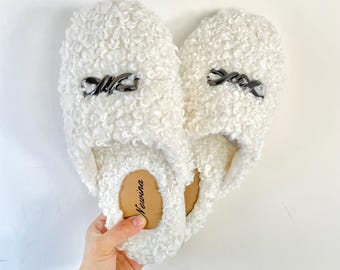 May include: White fluffy slippers with a silver chain detail and the word "Newina" on the insole.